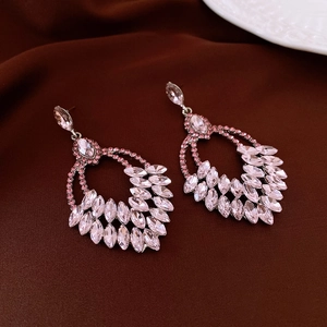 Detailed view of pink crystal wheat tassel earrings on premium brown pleated fabric