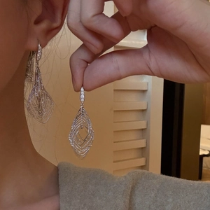 Detail of silver geometric leaf earrings with zircon inlay worn by a model