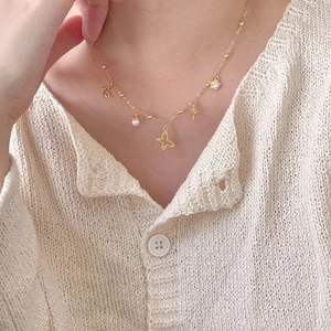 Close-up of a 925 sterling silver gold butterfly necklace with pearl and flower charms