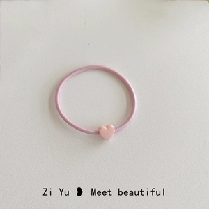 Dettaglio di un elastico per capelli rosa con un grazioso ciondolo a cuore in resina