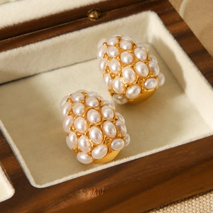 Detailed macro of gold-plated teardrop earrings with white pearls in a wooden box