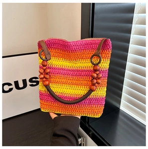 Close-up of woven straw handbag featuring rainbow gradient stripes and wood bead accents