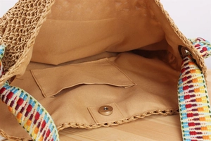 Detail view of woven beach bag interior featuring fabric lining and colorful ethnic strap