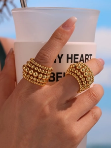 Close-up of layered gold bead chain ring on hand with elegant mirror finish detail