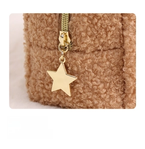 Close-up of golden star-shaped metal zipper on brown teddy fleece quilted makeup bag