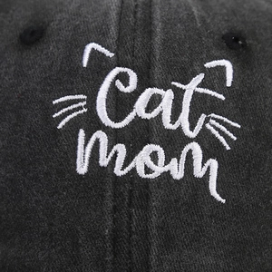 Close-up of white Cat Mom embroidery on a dark grey washed cotton baseball cap texture