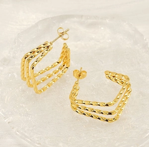 Detail of triple-layered twisted gold earrings with C-shape design and butterfly backs