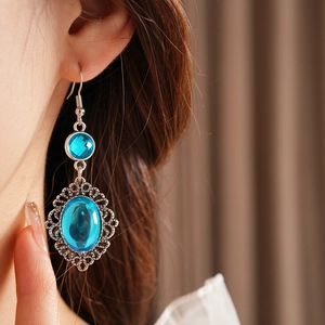 Detail of vintage bohemian silver earrings with oval blue resin stones worn by a model