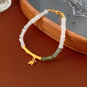 Detail of bamboo joint bracelet with white green jade beads and golden leaf pendant