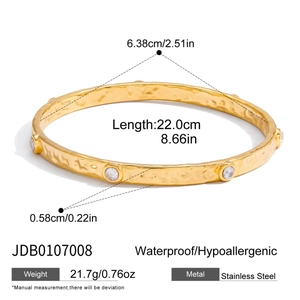 Detailed view of gold stainless steel bangle with hammered texture and inset crystals