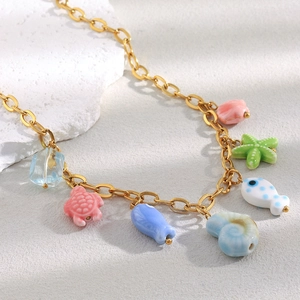 Macro detail of 18K gold-plated necklace with colorful ceramic marine animal charms