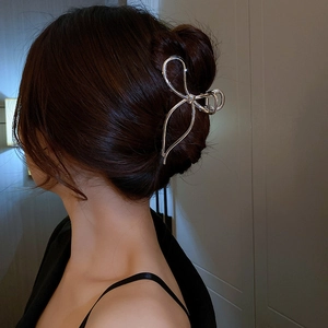 Detail of silver metallic bow hair claw clip worn on a bun hairstyle for chic look