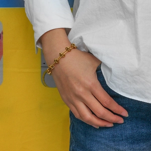 Detail of a gold knot bracelet with metallic chain links worn on a woman wrist