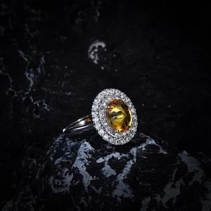Macro shot of oval yellow gemstone ring with double halo white zircon on black stone