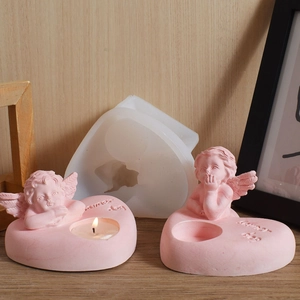 Silicone mold with finished pink heart-shaped angel candle holders on wooden background