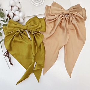 Close-up of elegant olive green and beige satin bow hair clips with long ribbons