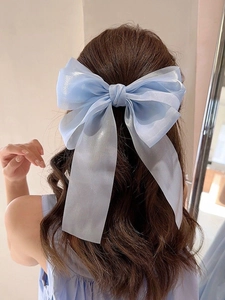 Macro detail of large light blue organza bow hair clip with iridescent pearl finish texture