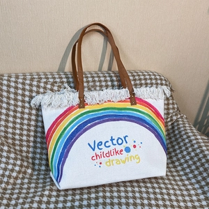 Detail of woven rainbow canvas bag for kids featuring white fringe and brown straps