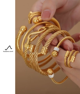 Détail de bracelets torsadés en acier inoxydable doré et ensemble de bagues sur modèle
