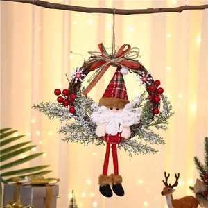 Detail of Christmas wreath featuring Santa doll, red berries and festive pine on wood
