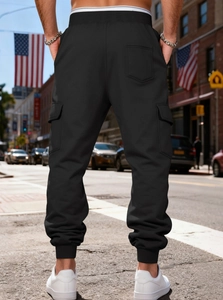 Street view of men's black cargo pants with large side pockets and ribbed cuffs