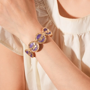 Detailed shot of vintage gold bracelet featuring purple inlay and golden butterfly charms