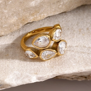 Macro shot of gold-plated stainless steel ring with pear-cut zircon on natural stone