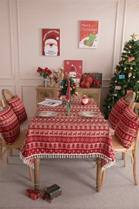 Macro detail of red Christmas tablecloth with reindeer jacquard pattern and white tassels