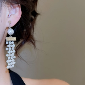 Detail of silver tassel clip-on earrings featuring white pearls and shimmering rhinestones