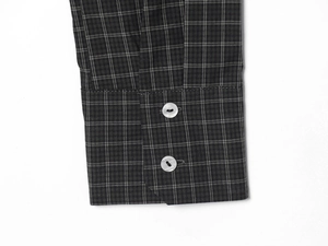 Detail of dark grey plaid shirt cuff featuring two pearlescent buttons and fine texture