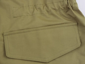 Détail de la parka vert armée montrant le tissu en coton et la couture de poche