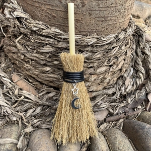 Detail shot of a mini wicca broom car charm with silver moon and star charms in nature