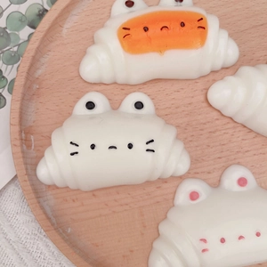 Cute cat croissant squishy stress toy on a wooden tray with a minimalist aesthetic