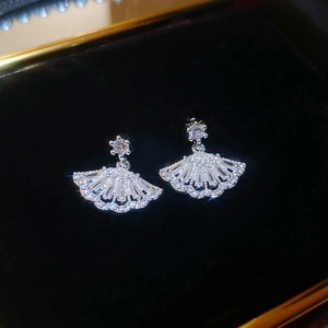 Macro detail of silver fan-shaped earrings with cubic zirconia on black velvet background