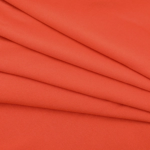 Détail du tissu orange corail avec une texture tissée fine et des plis diagonaux doux