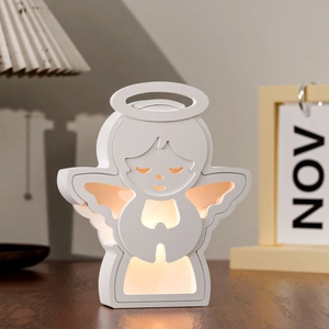 Détail de la veilleuse ange avec ailes lumineuses sur une table de chevet en bois