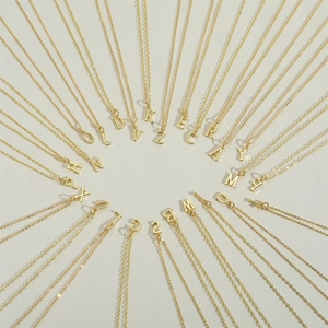 Collection of 26 delicate golden initial letter pendant necklaces on white background