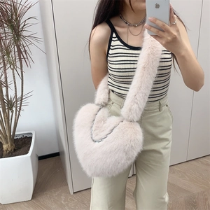 Mirror selfie showing the light pink plush heart-shaped crossbody bag with silver chain