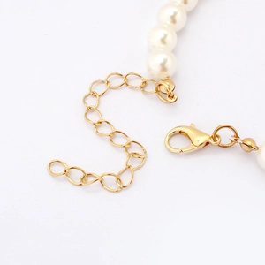 Close-up of the golden lobster clasp and adjustable extender chain on a pearl dog necklace