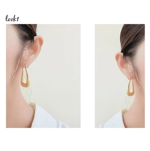 Detailed view of women wearing gold hollow U-shaped polished stainless steel earrings