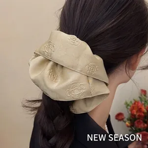 Elegant beige jacquard satin scrunchie with 3D rose pattern shown on hair