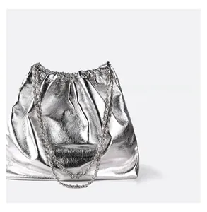 Detail of silver metallic drawstring tote bag with shiny crinkled texture and chain strap
