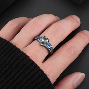 Vista macro de anillo corazón negro con piedra iridiscente e incrustación de ópalo