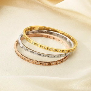 Close-up of three-tone stackable roman numeral bracelets with zircon pavé on silk fabric