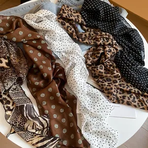 Chic assortment of polka dot and leopard print long skinny scarves on a white table