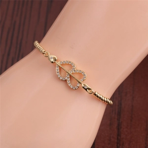 Detail of adjustable gold double heart arrow bracelet with zircon on a model's wrist