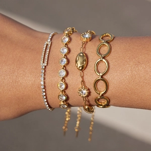 Dettaglio di bracciali sovrapposti in acciaio inossidabile placcato oro 18k con zirconi