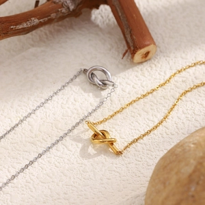 Detail of minimalist knotted pendants in gold and silver finish on textured background
