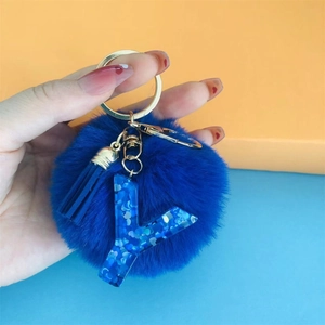 Detailed view of blue pompom and resin letter Y keychain with gold hardware