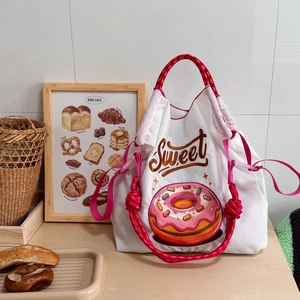 Detail of white nylon bag with pink donut embroidery and colorful braided handle
